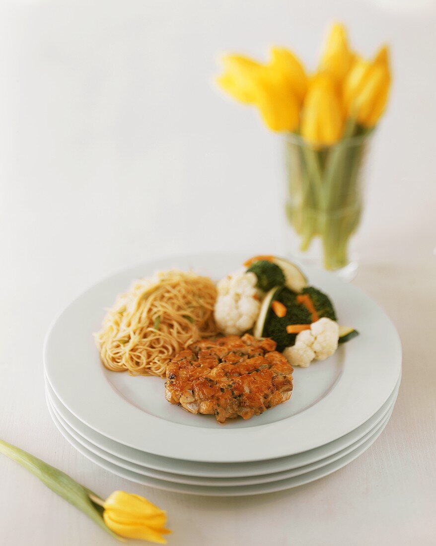 Salmon Cake with Pasta and Mixed Vegetables on Stacked Plates