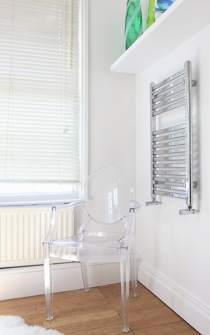 A Philippe Starck chair next to a towel rail in a bathroom