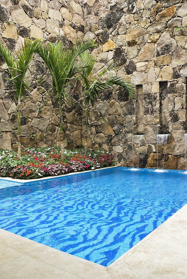 A pool with a small waterfall surrounded by a natural stone wall