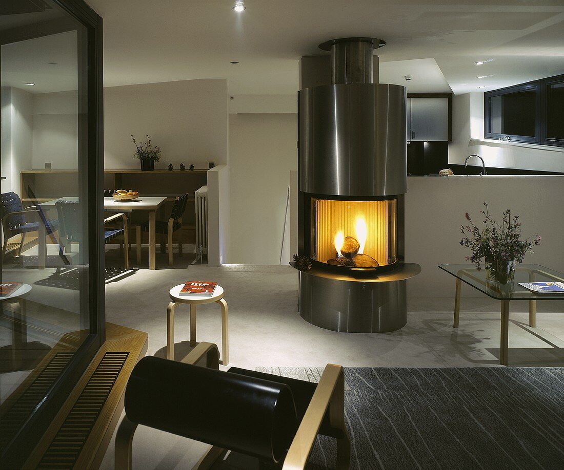 A fire burning in a stainless steel fireplace in an open plan living room-cum-dining room