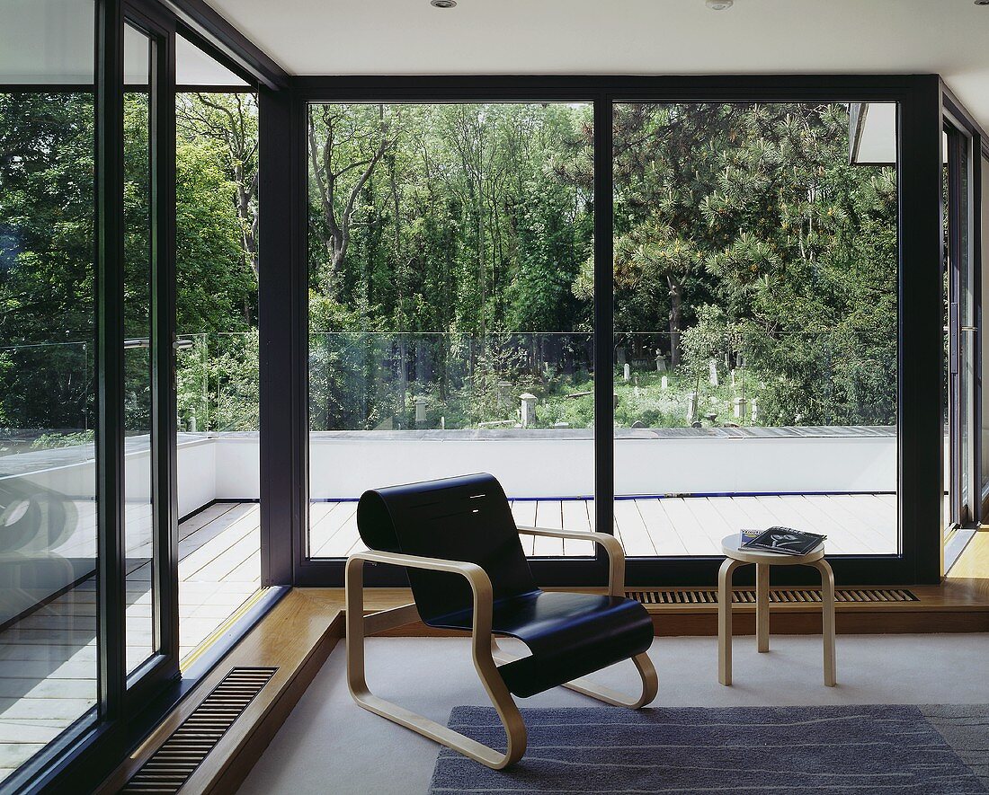 A Bauhaus armchair with a curved, black-painted seat in front of terrace doors
