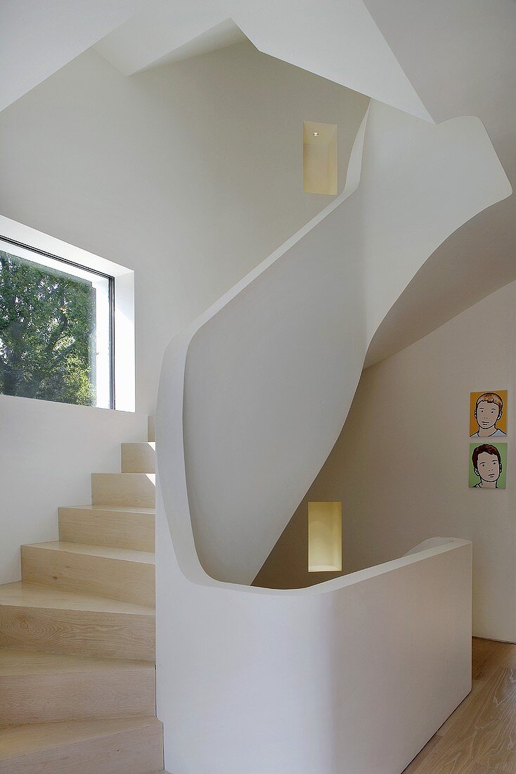 A curved staircase with wooden steps and a concrete designer bannister