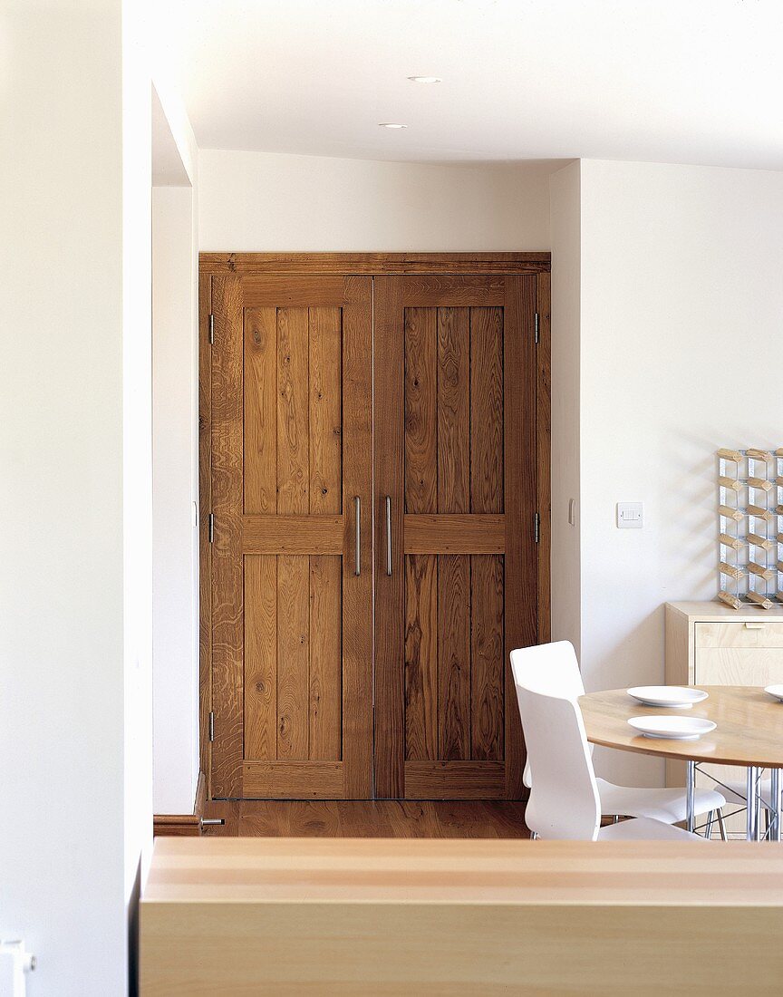 Build in cupboard with rustic wooden door and a set table with white chairs