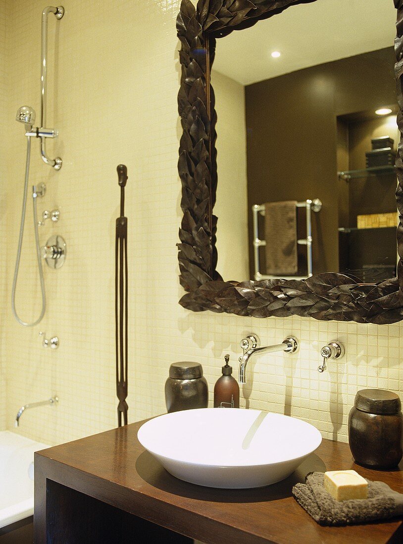 Bathroom with cream mosaic tile walls and built in show and washbasin on wooden ledge.