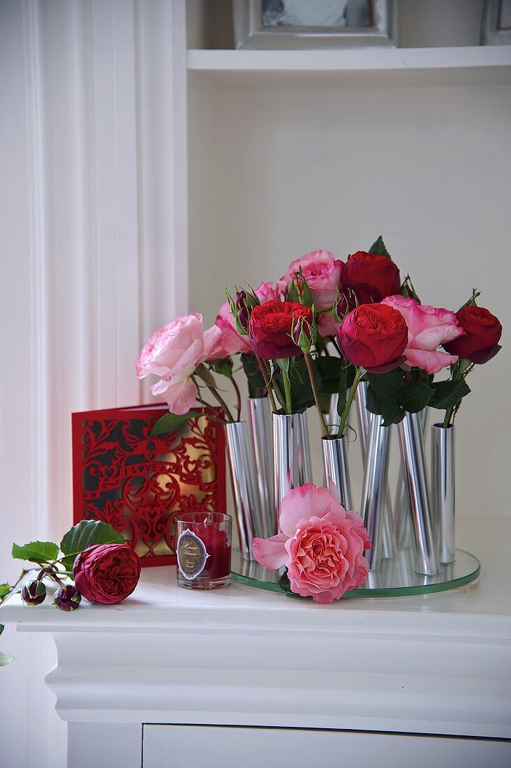 Einzelne Rosen in zylinderförmigen Vasen aus Metall