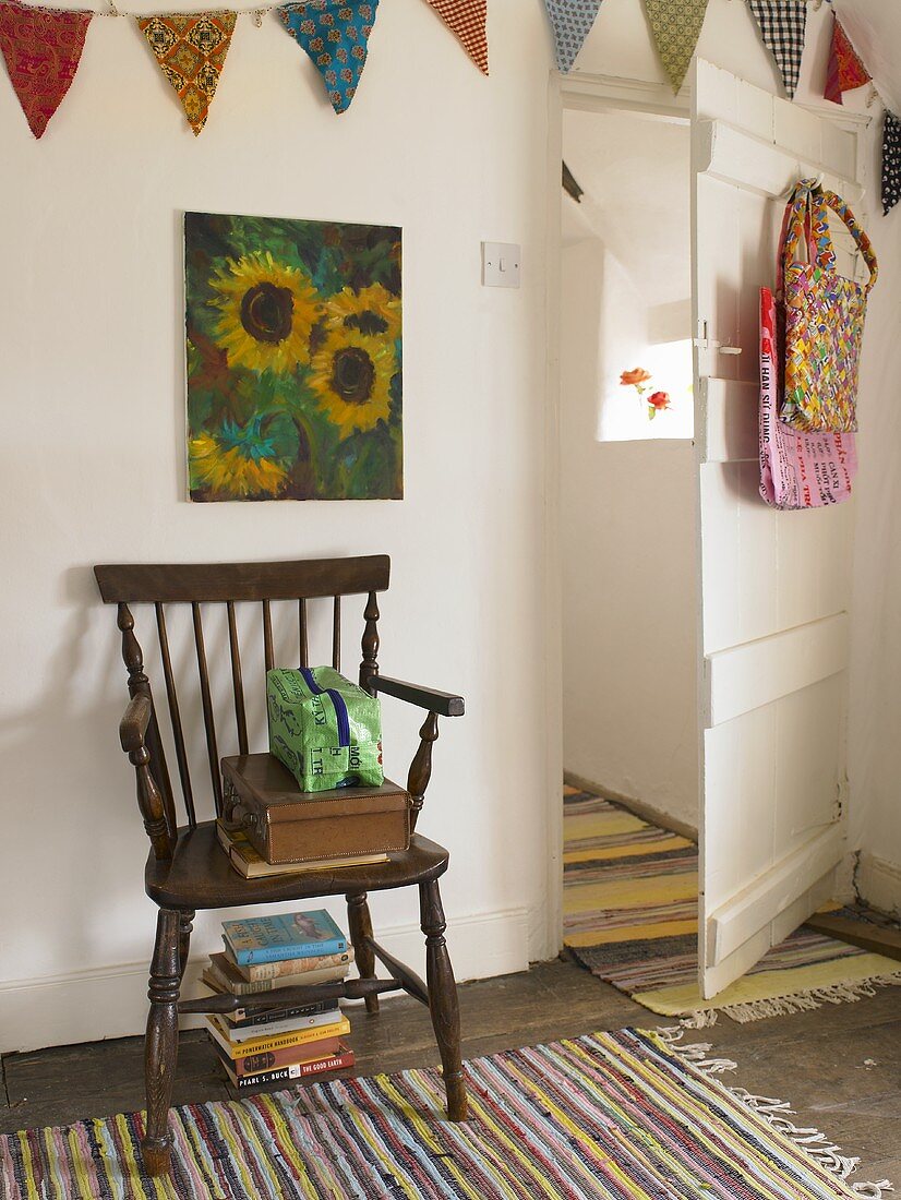 Rustikaler Stuhl aus Holz auf Teppich mit Streifenmuster und offenstehender weisser Tür