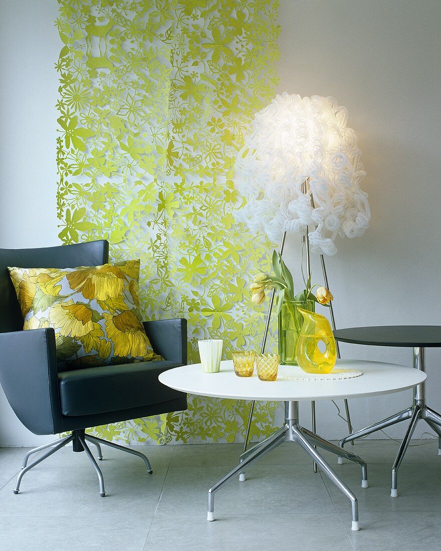 A white table and a black designer swivel chair in front of a green wall covering