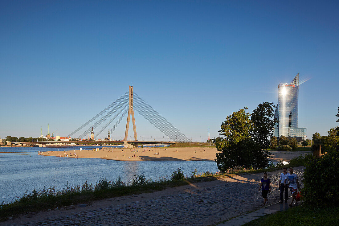 Beach of Kipsala at Vansu Tilts bridge, Svedbank office tower The Sun Stone on the right, Daugava river, old town in the back, view from Kipsala, Riga, Latvia