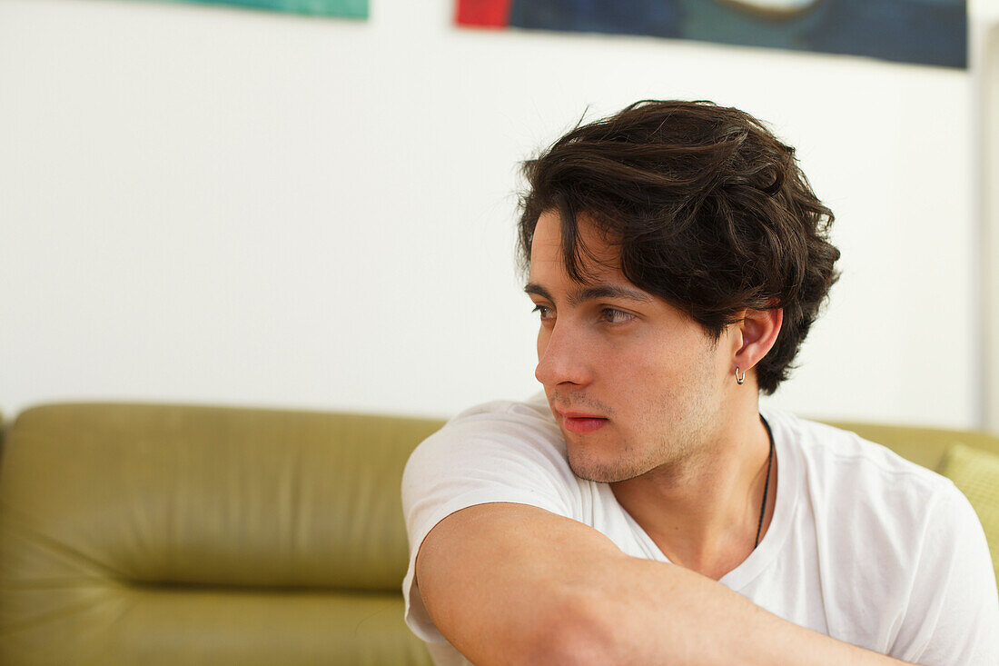 Young man sitting on the sofa, pensive