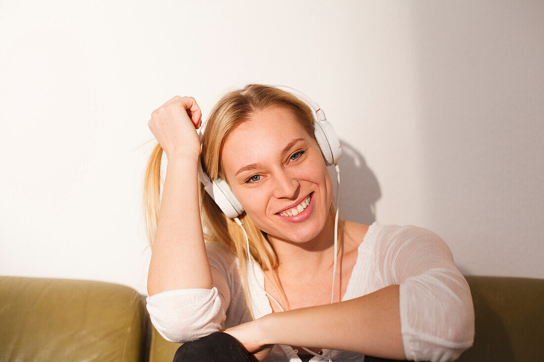 Young woman sitting on the sofa, listening to music