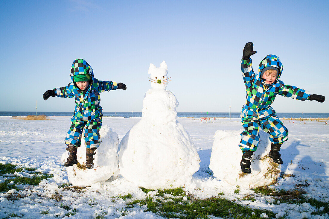 Boys jumping from a huge snowball, Cuxhaven, North Sea, Lower Saxony, Germany
