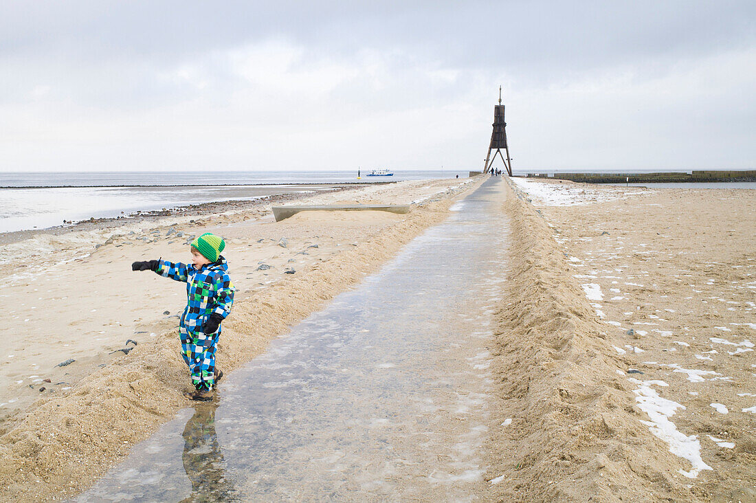 Boy pointing to North Sea, path to Kugelbake, Cuxhaven, North Sea, Lower Saxony, Germany