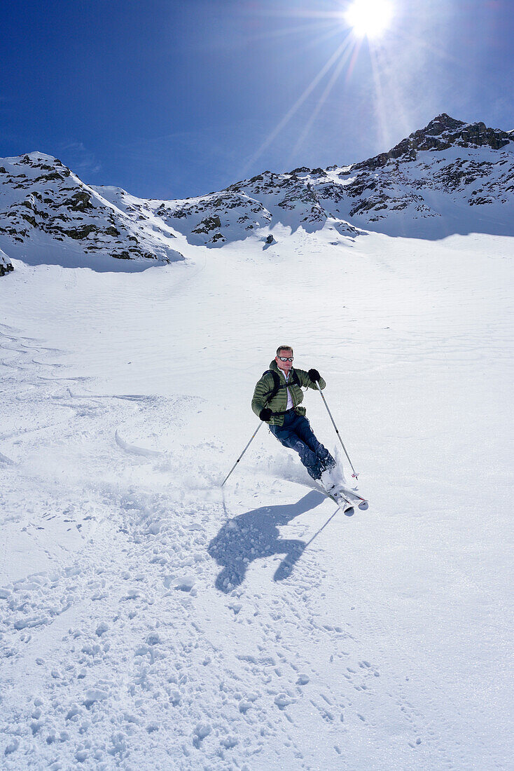 Man back-country skiing downhill from Piz Uter, Piz Uter, Livigno Alps, Engadin, Grisons, Switzerland