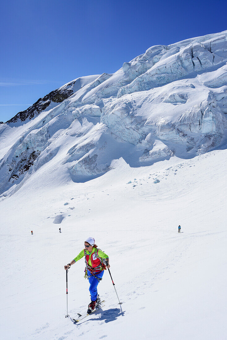Woman back-country skiing ascending towards Punta San Matteo, icefall in background, Punta San Matteo, Val dei Forni, Ortler range, Lombardy, Italy