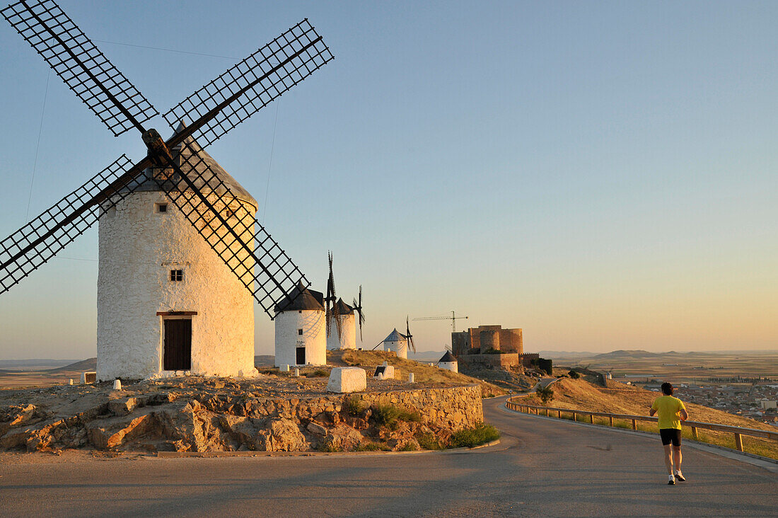 Jogger am frühen Morgen an den Windmühlen von Consuegra, Provinz Toledo, Kastilien, Spanien