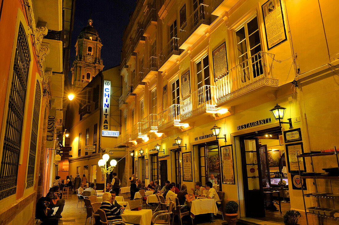 Schmale Gasse mit Tischen und Restaurants und Turm der Kathedrale von von Malaga im Abendlicht, Malaga, Andalusien, Spanien