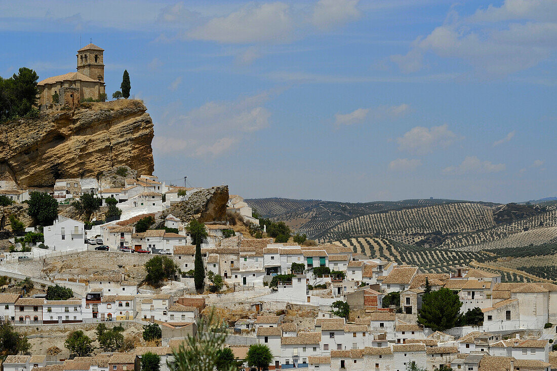 Kirche auf Felsen über einem Pueblo Blanco, weiße Häuser am Hang vor Olivenhainen, Montefrio, Andalusien, Spanien