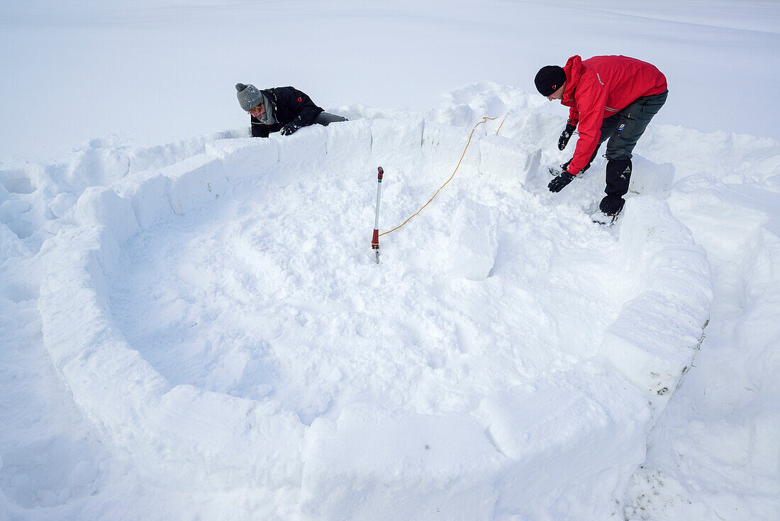 Zwei Personen bauen Iglu, Chiemgauer Alpen, Chiemgau, Oberbayern, Bayern, Deutschland