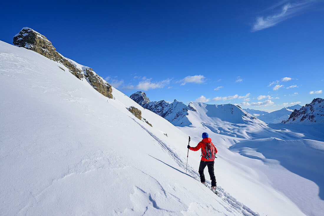 Woman back-country skiing ascending towards Monte Soubeyran, in background Aiguille Jean Coste, Monte Soubeyran, Valle Maira, Cottian Alps, Piedmont, Italy