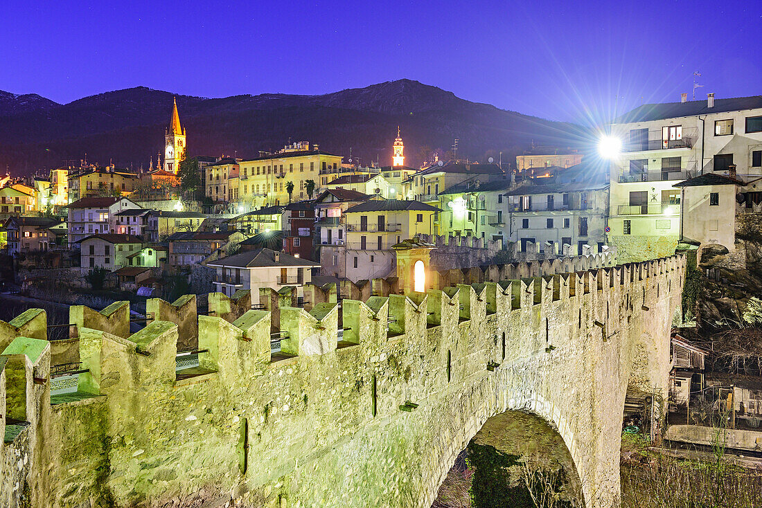 Illuminated village of Dronero with Ponte del Diavolo, Dronero, Valle Maira, Cottian Alps, Piedmont, Italy