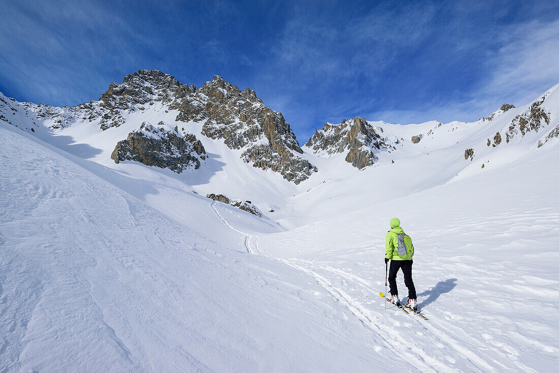Woman back-country skiing ascending towards Colle d'Enchiausa, view to Monte Oronaye, Valle Enchiausa, Valle Maira, Cottian Alps, Piedmont, Italy