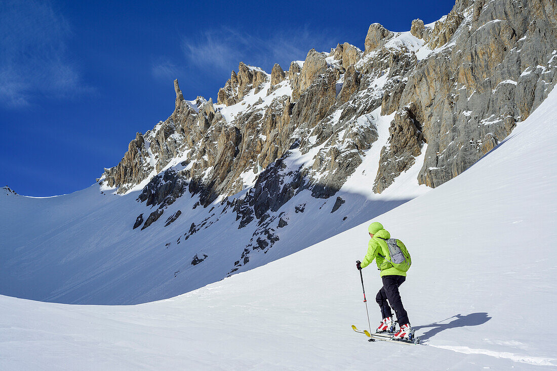 Woman back-country skiing ascending towards Colle d'Enchiausa, Valle Enchiausa, Valle Maira, Cottian Alps, Piedmont, Italy