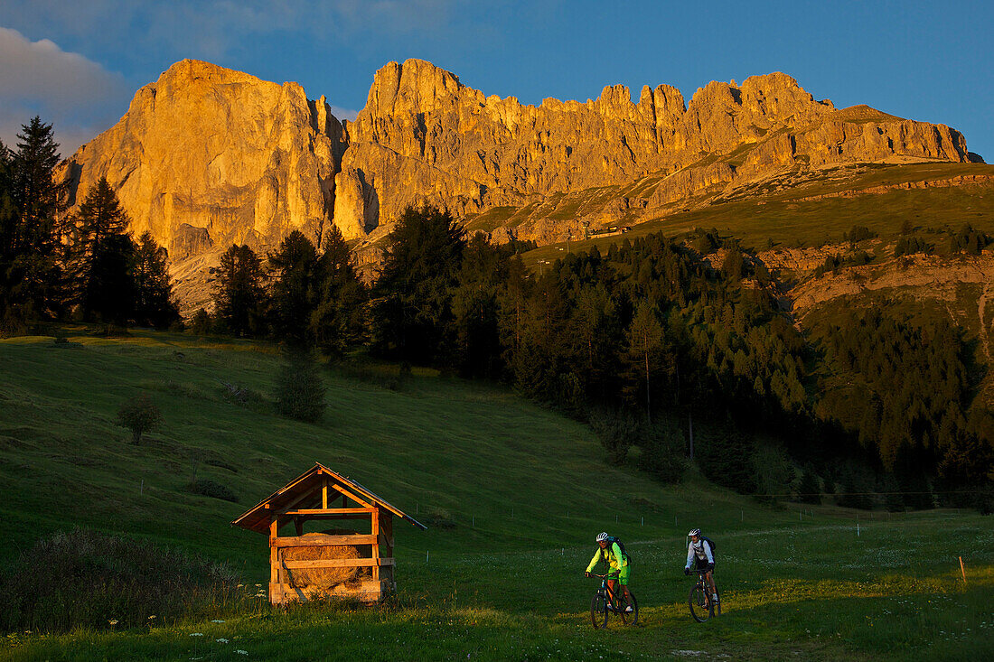 zwei Mountainbikerinnen im Abendlicht vor Latemar, Trentino, Italien