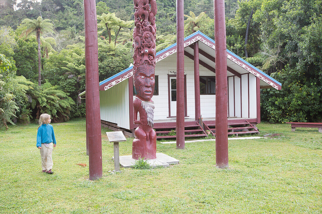 Ein Mädchen betrachtet die Maori Kultstätte (Marae) bei der Tieke Kainga Hütte. Kanu Trekking auf dem Whanganui River, North Island, Neuseeland