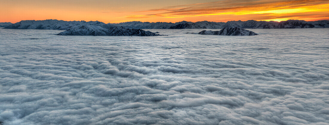 Sea of clouds cover Lake Wanaka, seen from Mount Roy, sunrise over Southern Alps, Otago, New Zealand