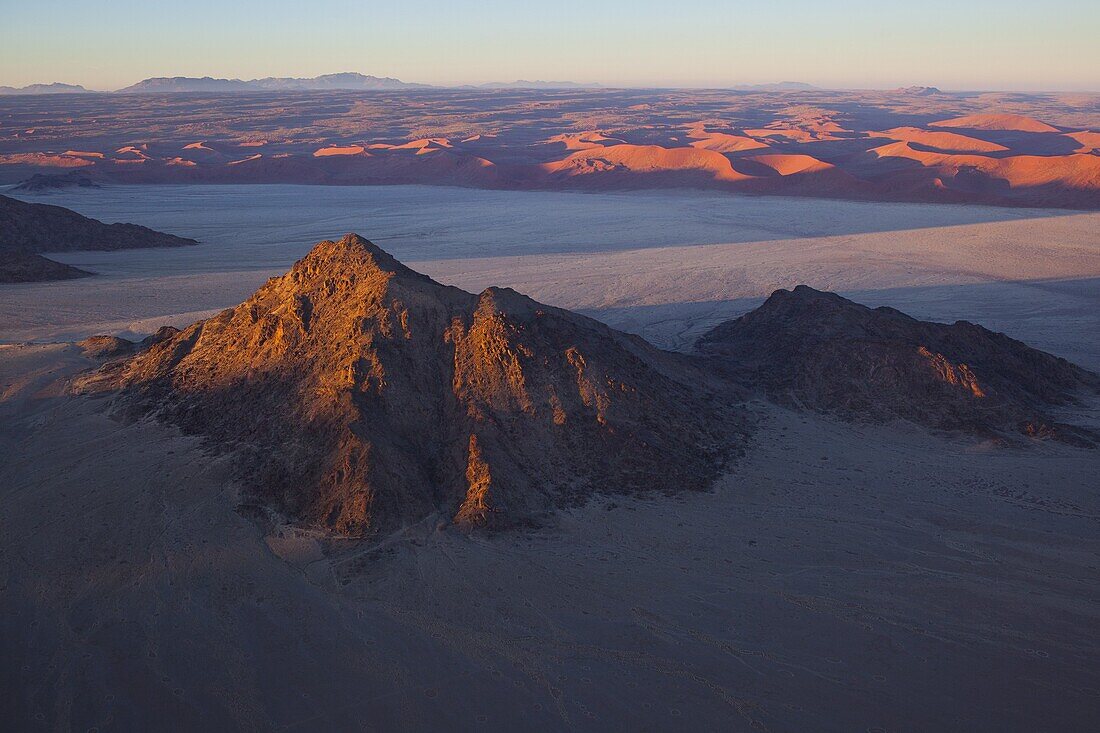 Rock outcrop and red sand dunes near Sossusvlei at sunrise, Namib-Naukluft National Park, Namib Desert, Namibia