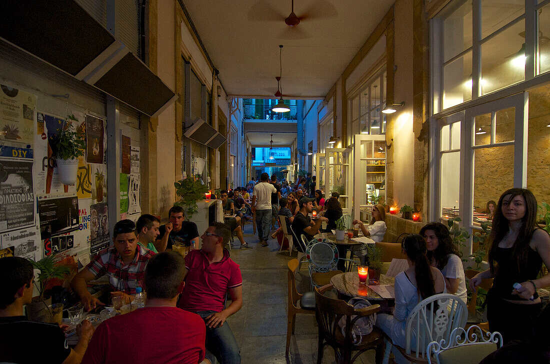 Viele Menschen sitzen am Abend in Tischen im Café Pieto in einem Durchgang in Leika Gaitonia in der  Altstadt Lefkosia, Nicosia, Zypern
