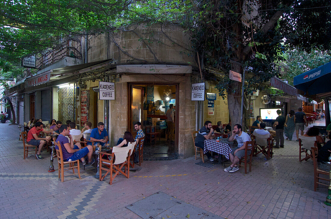 Menschen sitzen an Tischen auf der Strasse in einem Café in Leika Gaitonia in der Altstadt in Lefkosia, Nicosia, Zypern