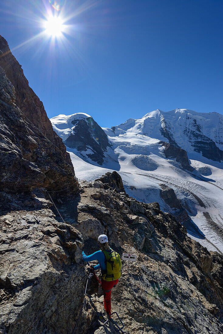 Woman climbing the via ferrata at Piz Trovat with view onto Piz Cambrena (3602 m), Piz Palue (3905 m) and Pers glacier, Engadin, Grisons, Switzerland