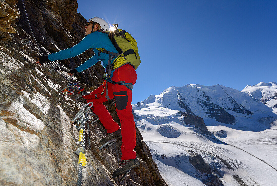 Woman climbing the via ferrata at Piz Trovat with view onto Piz Palue (3905 m), Bellavista (3922 m) and Pers glacier, Engadin, Grisons, Switzerland