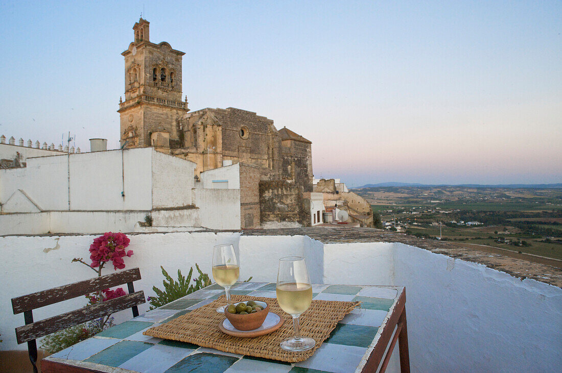 Wein und oliven auf einem Tisch auf dem Dach des Hotel La Casa Grande mit Blick zur Kirche San Pedro ein der weissen Stadt Arcos de la Frontera, Provinz Cadiz, Andalusien, Spanien