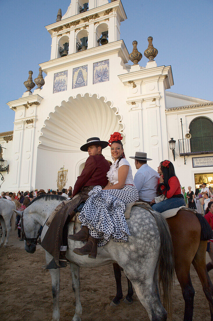 Paar in Flamenco Kleidung auf Pferd, Pilger auf Pferden  bei der Wallfahrt zu Pfingsten zu 'Nuestra Senora de El Rocio' vor der Kirche Eremita del Rocio, El Rocio, Huelva, Andalusien, Spanien