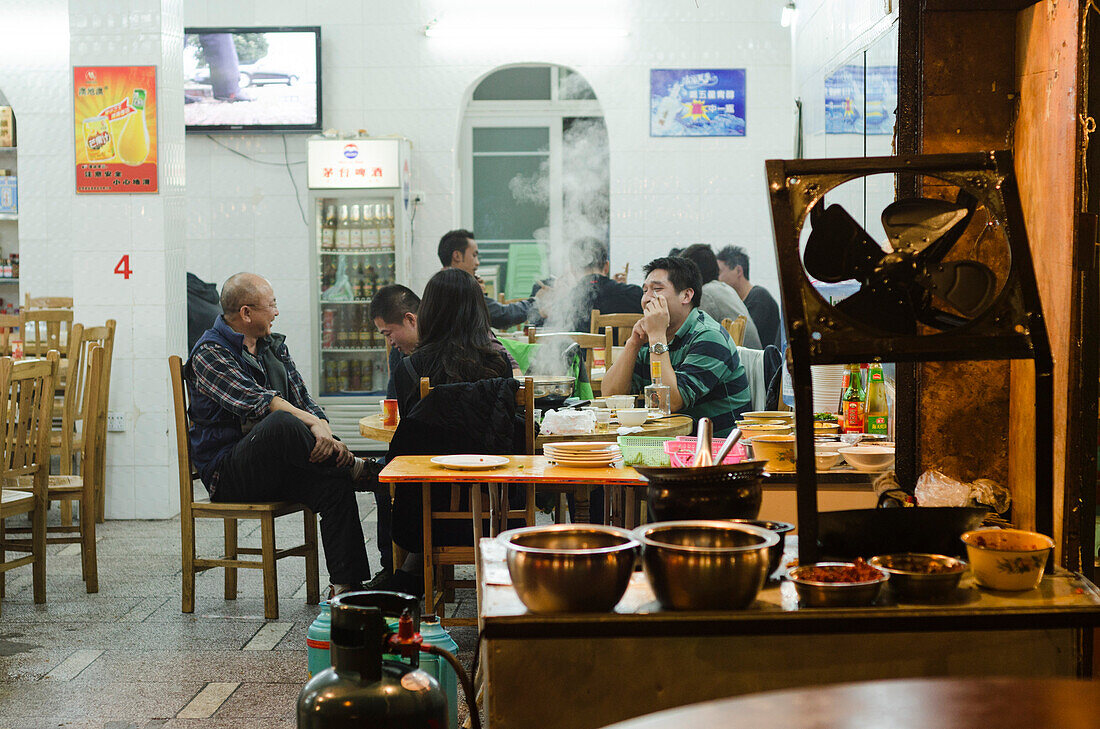 Leute essen in einem offenen Restaurant am Nachtmarkt der Stadt Kaili, Provinz Guizhou, China