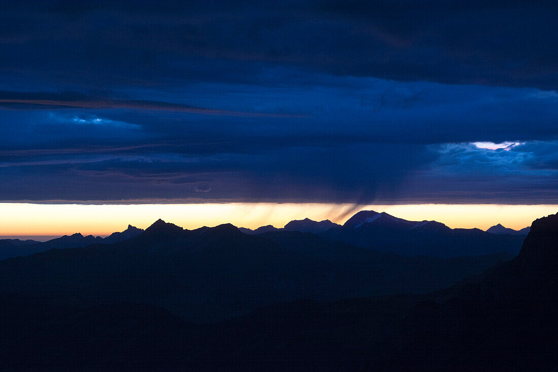 Kurz vor Sonnenaufgang liegt eine tiefe Wolkendecke über Berggipfeln, von links nach rechts die Gipfel Hinderi Spillgerte, Giferspitz, Ladholzhore und Albristhorn, Berner Alpen, Kanton Bern, Schweiz
