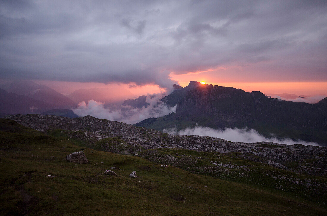 Die Sonne versinkt hinter dem Druesberg, im Vordergrund die Karstfelder des Bergs namens Silberen, Glarner Alpen, Kanton Schwyz, Schweiz