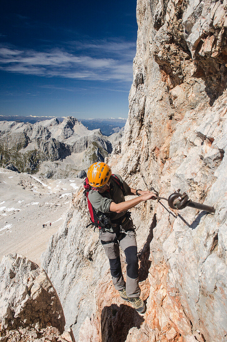 An alpine hiker or climber on the upper part of the ferrata called Bamberger Weg leading to the summit of the Triglav, Julian Alps, Slovenia