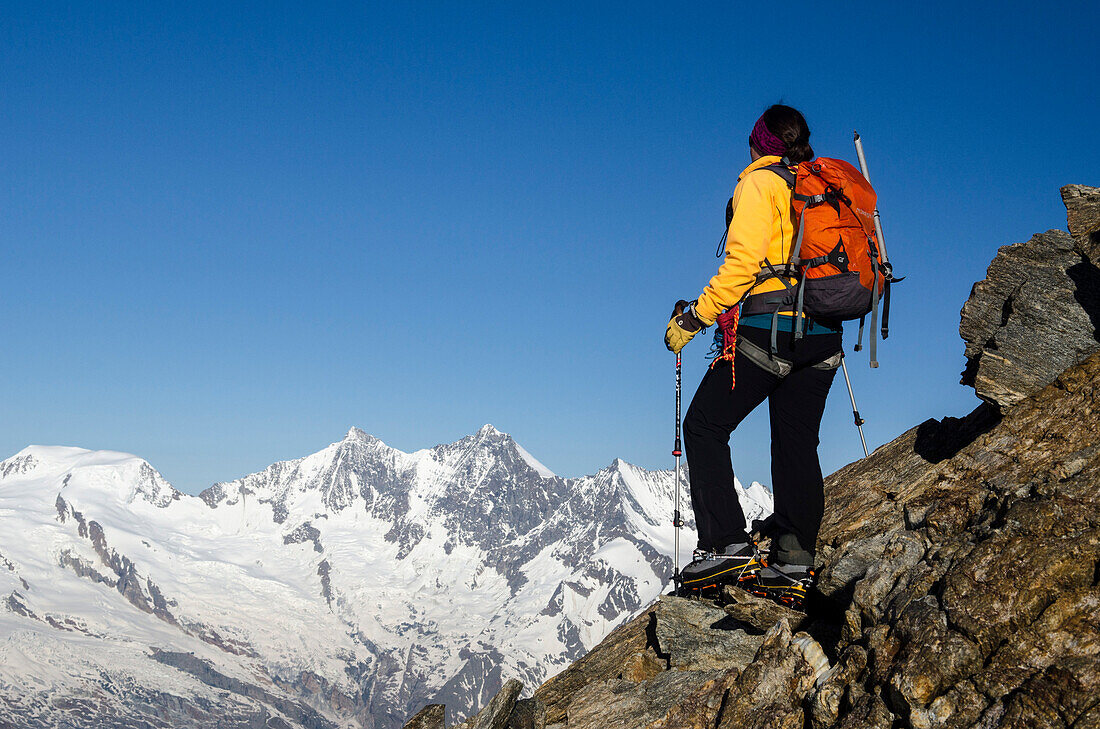 A female alpinist on the south ridge of the Weissmies, in the background from left to right, Alphubel, Taeschhorn, Dom and Lenzspitze, Pennine Alps, canton of Valais, Switzerland