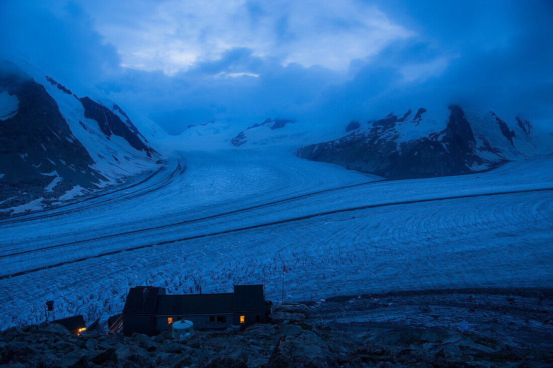The Concordia Hut while night is falling, sitting high above the large flat space called Concordia, where major arms of the Great Aletsch Glacier converge, Bernese Alps, canton of Valais, Switzerland