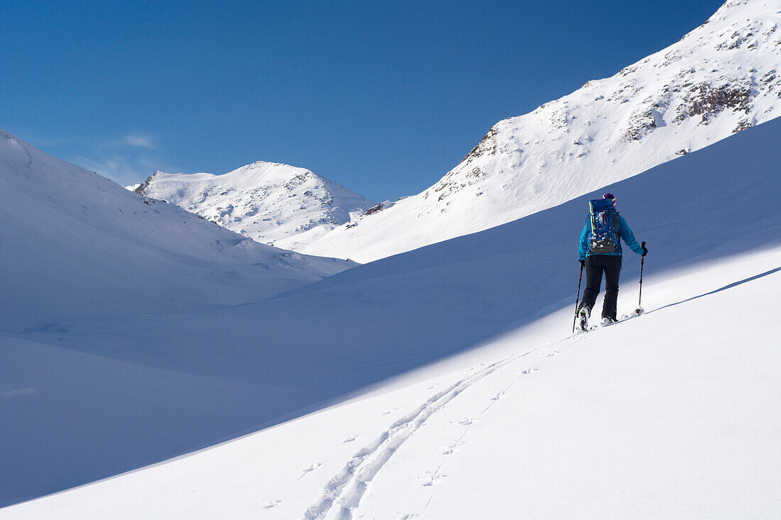 Eine Skitourengängerin zieht ihre Aufstiegsspur im Val Camadra, Lepontinische Alpen, Kanton Tessin, Schweiz
