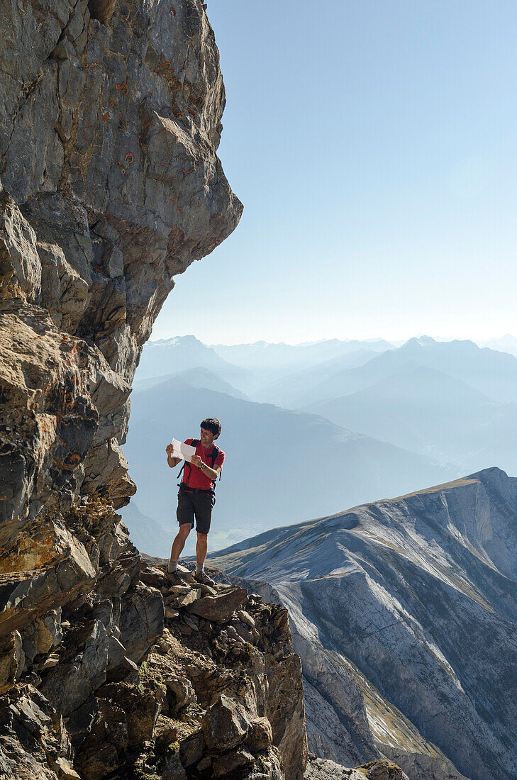 A young alpine hiker looking for a possible scrambling route to reach the summit of Felsberger Calanda, massif of Calanda, Grison Alps, cantons of Grison and St. Gallen, Switzerland