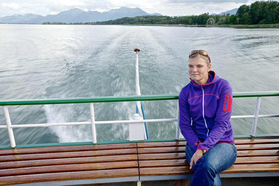 Frau sitzt auf einer Bank einer Fähre auf dem Chiemsee, Chiemgau, Bayern, Deutschland