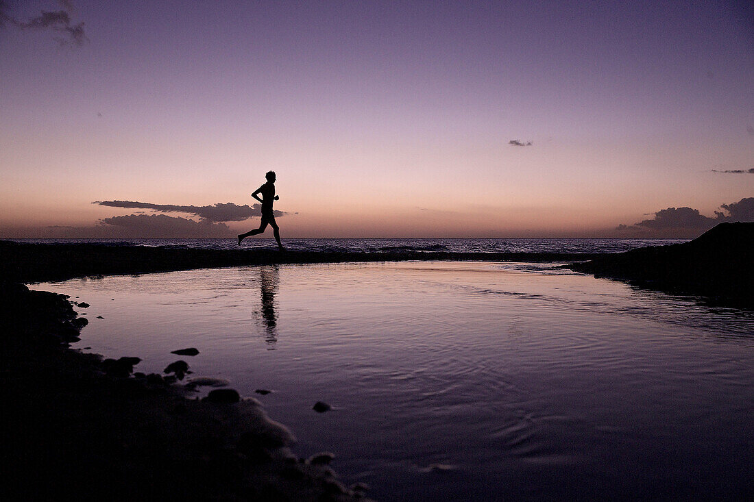 Man running along beach in sunet, Dominica, Lesser Antilles, Caribbean