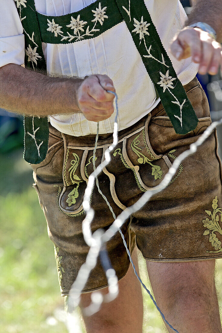 Man wearing traditional clothes pulling a wire, Viehscheid, Allgau, Bavaria, Germany