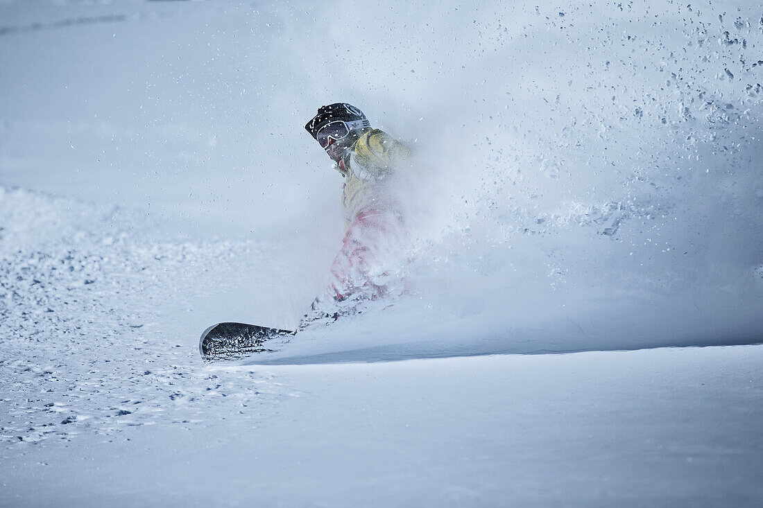 Young male snowboarder riding through deep powder snow in the mountains, Pitztal, Tyrol, Austria
