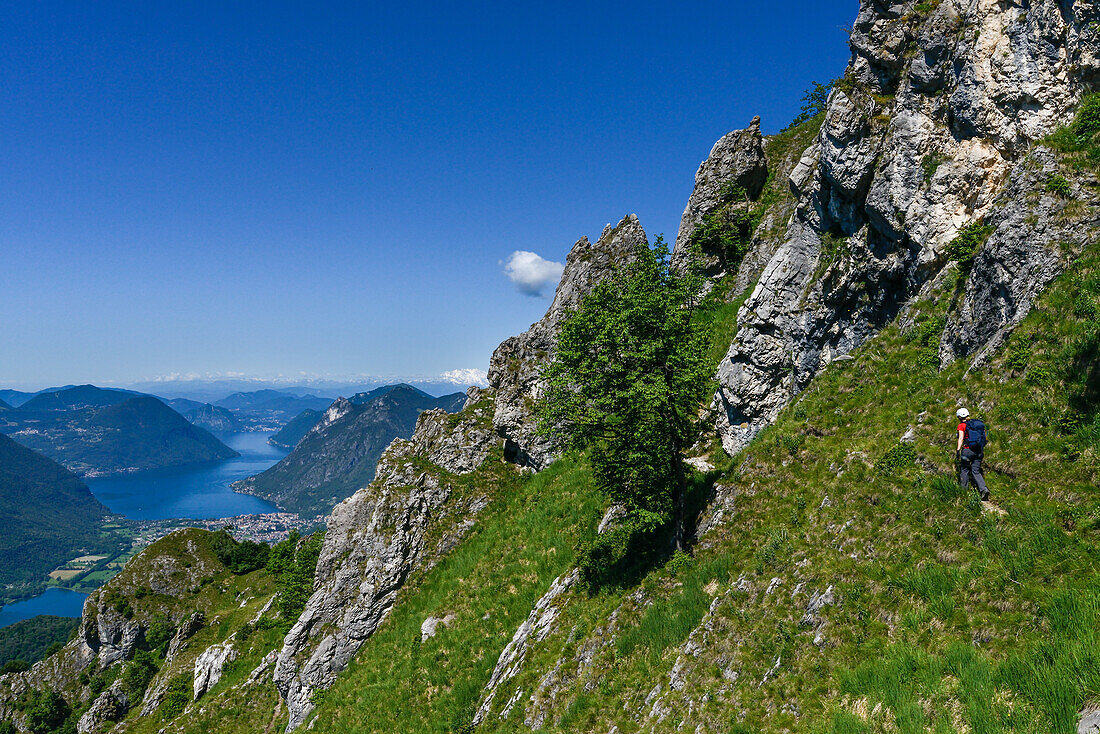 Hiker in front of Lake Lugano with the highest Swiss mountain, the snow-capped Dufourspitze (4634 m) in the Monte Rosa massif, Italy and Switzerland