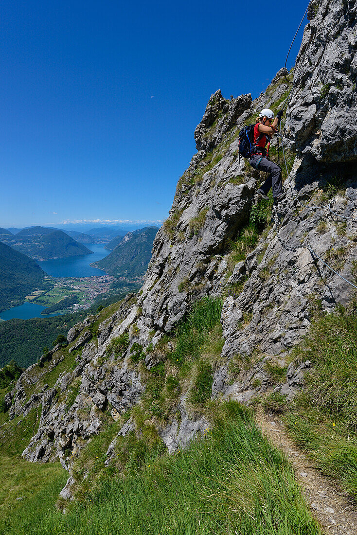 Woman climbing the Via ferrata del Centenario in front of Lake Lugano, Italy and Switzerland